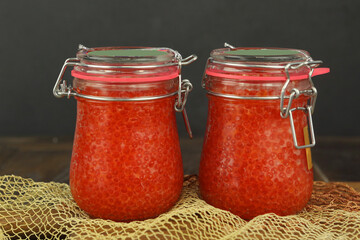 natural red caviar in glass jar closeup photo on kitchen board