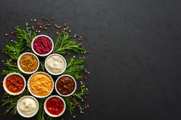 Different types of sauces in bowls with seasonings, rosemary and dill, thyme and and peppercorns, top view, copy space
