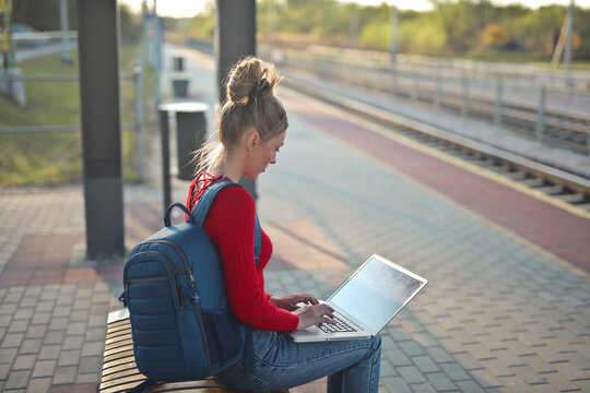 young woman uses a computer in a train station