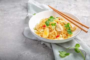 Stir fried noodles with chicken and vegetable in white bowl