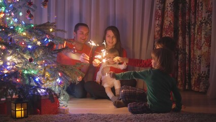 Happy big family with sparklers celebrating Christmas near the fir tree