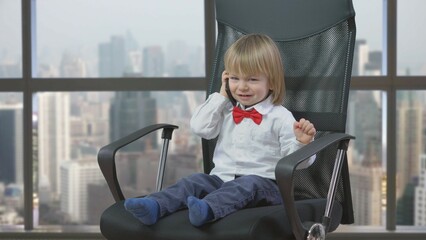 Portrait of child with red bow sit on business chair and talking on phone