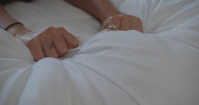 Sensual lady Hands compressing white duvet sheets.  Feel desire and enjoyment