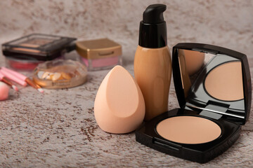 Beauty blender for applying bb cream or concealer and cosmetics on a marble background. Foundation, face powder, eye shadow, blush and lash mascara. Beauty concept. Fashion. Place for text.