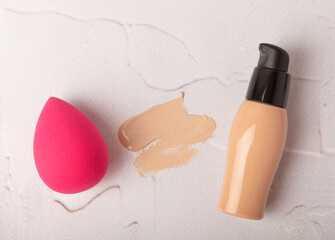 Obraz premium Liquid foundation for makeup and sponge blender for makeup. Foundation beauty face makeup application, perfect makeup tool. Beauty blender,bb cream or concealer on marble texture background.