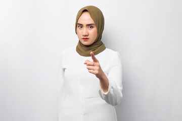 Angry young beautiful Asian Muslim woman 20s wearing hijab points her finger at the camera isolated...
