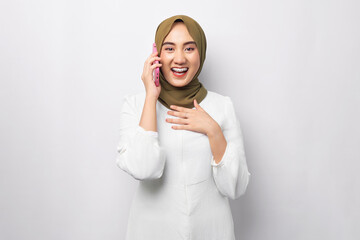 Beautiful cheerful Asian Muslim woman wearing hijab talking on mobile phone and conducting pleasant...
