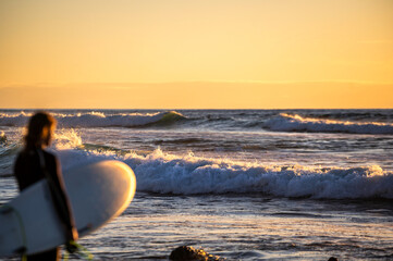 Wilde Brandung eines Meeres im Sonnenuntergang  mit unbekanntem Surfer