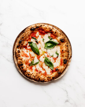 Freshly baked sourdough pizza Margherita topped with fresh San Marzano sauce, Pecorino cheese, Fior Ddi Latte Mozzarella, fresh basil and olive oil on a plate