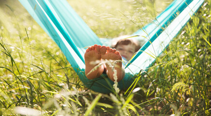 child girl  lies in a hammock and have fun in the park in the summer