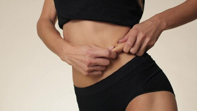 Side view of unrecognizable woman touching and pressing skin on her stomach. Shot with RED helium camera in 8K. 