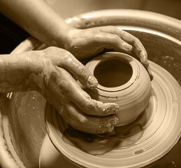 Master's hands mold a jug on a potter's wheel