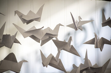 Japanese folded Origami cranes hanging on with strings. Hundreds handmade paper birds isolated with copy space. 1000 thousand crane sculpture topic. Symbol of peace, faith, health, wishes, hope