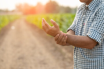 Injuries or Illnesses that can happen to farmers while working. Man is using his hand to cover over wrist because of hurt,  pain or feeling ill.