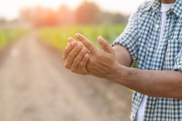 Injuries or Illnesses that can happen to farmers while working. Man is using his hand to cover and press on hand because of hurt,  pain or feeling ill.