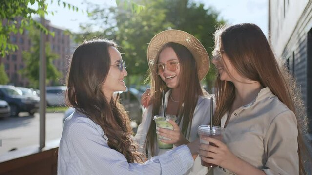 Three young beautiful woman girl female hipster friends in summer clothes walking meeting laughing drinking fresh cocktail In street outdoor. Friendship travel having fun. happiness, freedom, love 