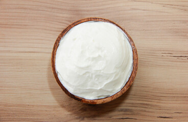 White fermented milk yogurt in a decorative brown plate on a wooden background