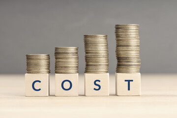 Increase of cost concept. Text on Wooden blocks and Stacking coins. Copy space