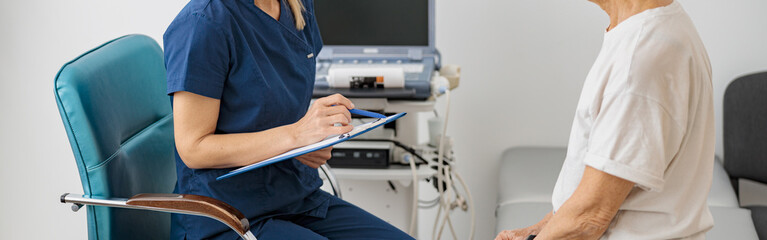 Doctor ultrasound specialist makes notes in clipboard during patient appointment in clinic
