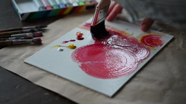Woman hands painting with acrylics on canvas. Red color, abstract drawing