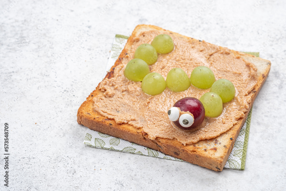 Wall mural Funny worm sandwich toast with peanut butter and green grapes - Wall murals