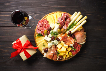 Christmas food Antipasto with red wine and presents. Cheese and meat with olives at serving board. Romantic christmas or New Year dinner for couple.