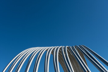 Aluminum tubes arching overhead against pure and deep blue sky.