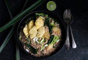Pineapple fried rice has minced pork and vegetable in plate on stone table.