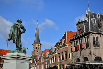 Close-up on the statue of Jan Pieterszoon Coen (1587, 1629), historic houses and the tower of Grote kerk church in Hoorn, West Friesland, Netherlands. The statue was unveiled in 1893.