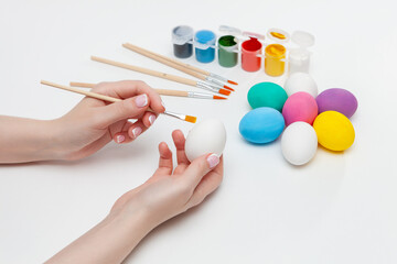 Easter egg in the hands of a woman. A woman paints an Easter egg with watercolors. Close-up