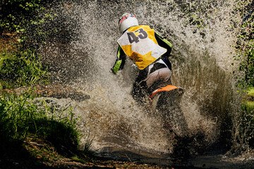 back rider enduro motorcycle riding puddle of water and mud, splashes and drops