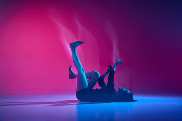 Inner world. Young talented woman dancing, performing over gradient pink studio background in neon with mixed lights. Concept of contemporary dance style, art, aesthetics, hobby, creative lifestyle