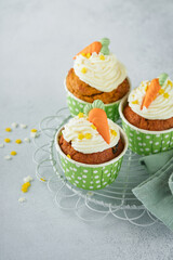 Carrot cake cupcakes for Easter. Carrot cupcakes with cream cheese frosting decorated with tiny...