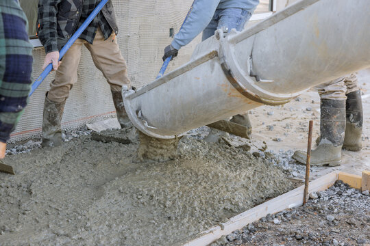 It is concrete mixing truck pouring concrete around new house that will be used for pavement