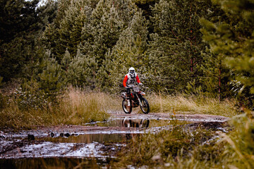 enduro racer riding a dirty trail motocross race in forest