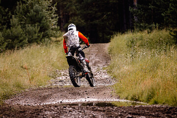 back enduro racer riding a dirty trail in motocross race - obrazy, fototapety, plakaty