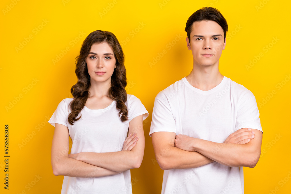 Poster Photo of two young models business partnership folded arms wear same white t-shirts enjoy their job together isolated on yellow color background