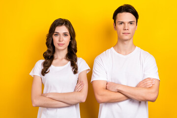 Photo of two young models business partnership folded arms wear same white t-shirts enjoy their job together isolated on yellow color background