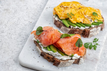 Scrambled eggs with smoked salmon and avocado on a whole wheat toast