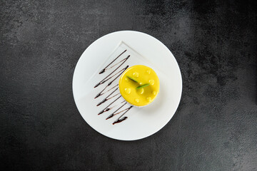 Mini mango cake on white plate on black concrete background. Mango cheesecake in minimal style on...