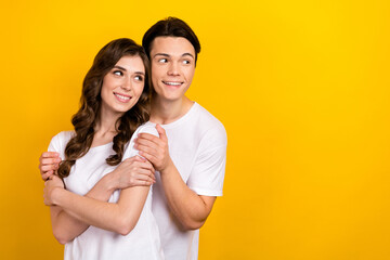 Photo of pretty charming husband wife dressed white t-shirts hugging looking empty space isolated yellow color background