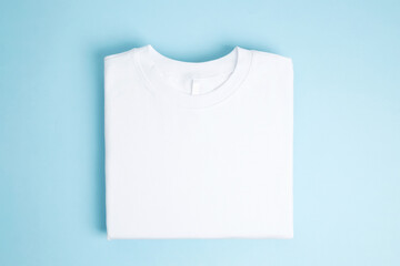 Basic folded white t-shirt blue background. Mock up for branding t-shirt. Copy space