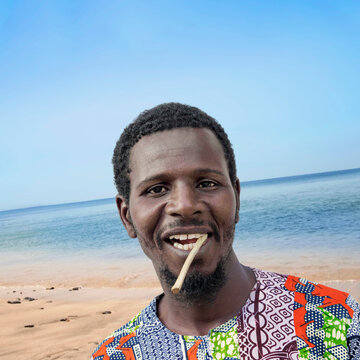 African man holding a miswak between his teeth at the beach (traditional teeth cleaning twig, also called sothio or sotio), photo