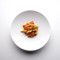 top view plate of pasta with tomato and basil on a white background
