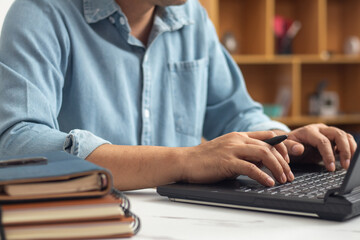 Male hands typing on laptop keyboard and surfing internet on desk, business concept and technology, internet network communication