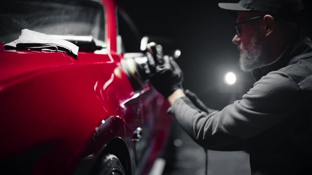 Car Ad Style Footage of a Professional Car Detailer Using an Electric-Powered Polishing Machine to Work on a Fender of a Beautiful Red Sportscar After Washing and Detailing the Vehicle