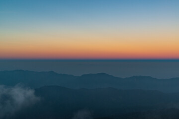 Panoramic twilight view while morning mist covered partly mountain seen from the highest peak of Doi Pha Hom Pok, Fang, Chiang Mai, Thailand.
