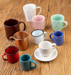 Assorted colorful cups and mugs over wooden table