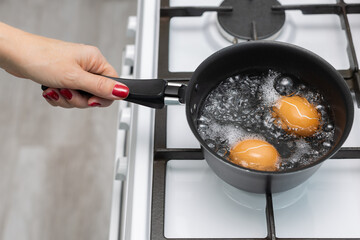 man boils an egg in water in the kitchen