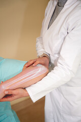 Pretty female orthopedist with patient in her office. Young doctor neurologist examining her patient. Neurologist checks the reflexes of a middle age female patient.